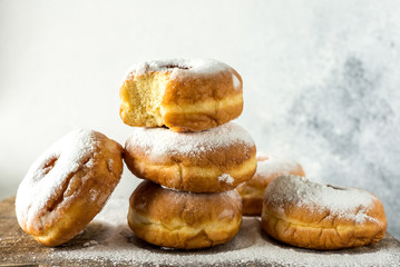 Lush sweet homemade donuts sprinkled with powdered sugar on a wooden background