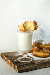 tasty sweet homemade donuts with a mug of milk on a wooden background