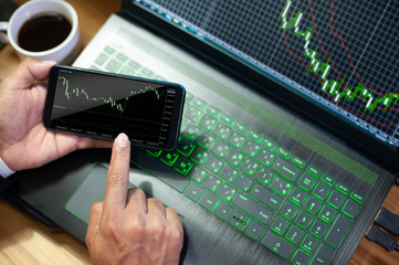 Businessman treading stock market by mobile phone Analysis economy data with computer screen