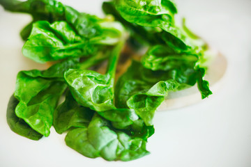 There are fresh spinach leaves on the white table in the kitchen. Ingredient for cooking. Useful...