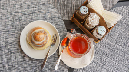Sweet round bun and cup of tea on a beautiful napkin background. Bakery concept.