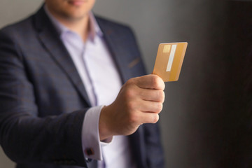 Man in an office suit holds out a Bank card