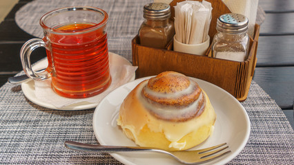 Sweet round bun and cup of tea on a beautiful napkin background. Bakery concept.