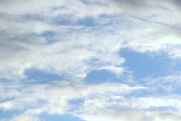 Clouds in the blue sky at sunset or dawn backlit by the sun. Place for text and design.