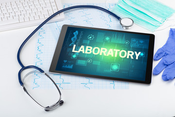 Tablet pc and medical stuff with LABORATORY inscription, prevention concept