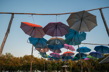 Group of colorful umbrellas hanging on a rope isolated from blue sky background. colored umbrellas isolated from bright sky background.