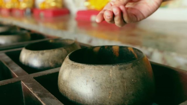 Man hand put coin in monk's alms-bowl. Buddhist culture for good luck and make merit.