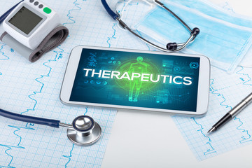 Tablet pc and doctor tools with THERAPEUTICS inscription, coronavirus concept