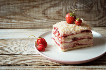 a piece of Napoleon cake with strawberries on a wooden background