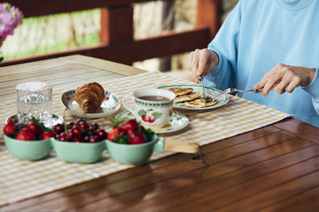 Healthy breakfast in the garden in summer. A woman eating pancakes