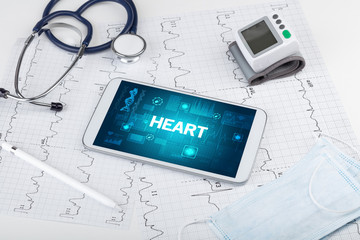 Tablet pc and medical stuff with HEART inscription, prevention concept