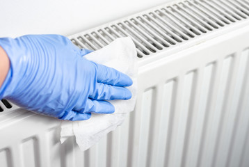 Man with surgical gloves cleaning the radiator with disinfectant wet wipes . Preventing  of bacteria and   coronavirus spreading .