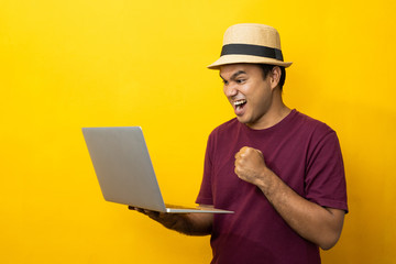 Asian man red shirt with hat using laptop on isolated yellow background.