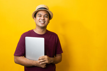 Asian man red shirt with hat using laptop on isolated yellow background.