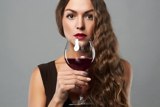 Beautiful middle aged woman with curly hair style drinking red wine