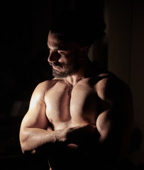 Fototapeta na wymiar muscular young man in the dark, portrait of a young man in the dark