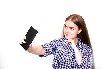 A young girl in a plaid shirt with long hair stands on a white background and holds a smartphone in his hand. Girl makes a selfie. Visas front and rear of the girl. Lips  duck