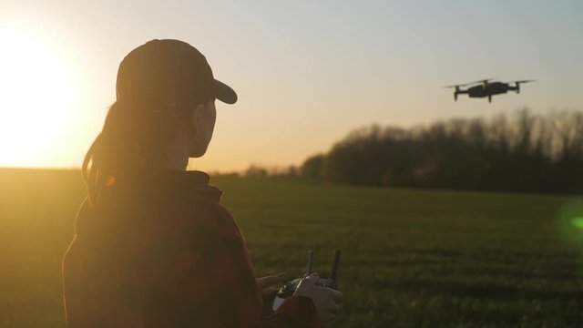Silhouette of a girl farmer using a drone in a wheat field at sunset. Concept technology innovations for increasing productivity in agriculture.