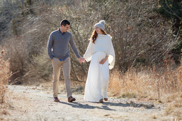 Pregnant couple walking ourdoors in a natural setting. 