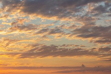 Sunset sky covered with orange puffy clouds in the evening.