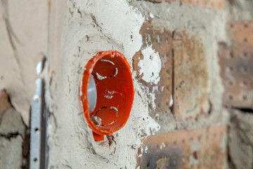 Socket orange boxes with wires in a wall. Cabling installation of electrical wires sticking out from electrical sockets hole on brick wall.