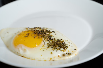 fried chicken egg on a white plate on a black background