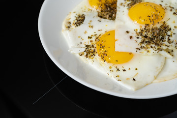 fried chicken egg on a white plate on a black background