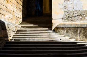 City detail of the beautiful mediterranean Salerno in South Italy. A beautyful ancient stairway defined by the contrast of the sun light and its shadows leads to the secondary entrance of the church