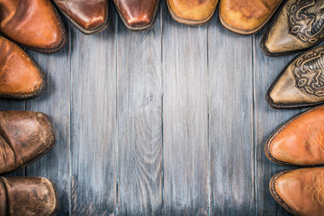Old retro leather cowboy boots on aged textured wooden floor for background. Wild West nostalgic...