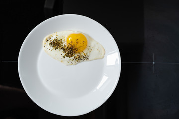 fried chicken egg on a white plate on a black background