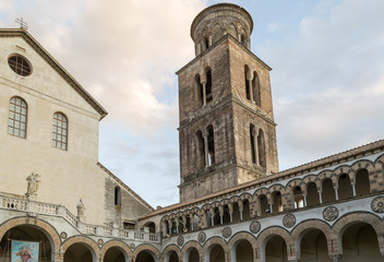 Fototapeta na wymiar Salerno, Italy. View of the cloister of San Matteo Cathedral and its arab-normann style beautiful bell tower seen from under its porch. A everyday scene of this mediterranean pretty town