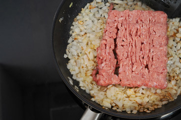 minced meat fried in onions in a black pan