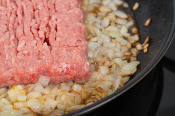 minced meat fried in onions in a black pan