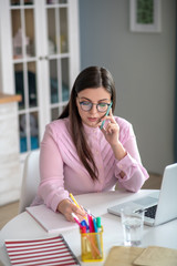 Woman in a pink blouse wearing eyeglasses sitting at the table