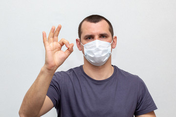 man in medical mask on his face showing ok on a white background.