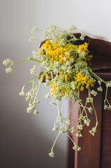 Wild flowers in a reusable, paper bag. Beautiful flowers hanging off a bag on the wooden cabinet. 