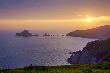 Rocky islands and peninsulas in the ocean at sunset.