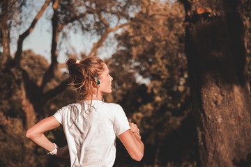 Giovane ragazza runner si allena da sola e concentrata indossando auricolari in mezzo alla natura...