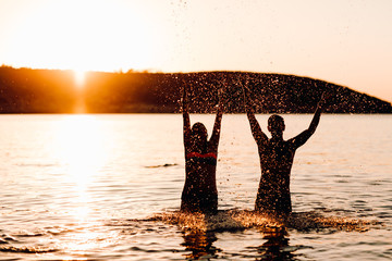 Pareja jugando con el agua en el mar al atardecer