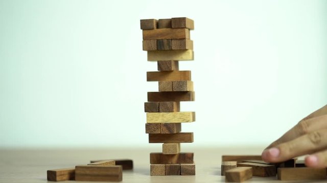 Business risks concept. Hand pulls out wooden brick with jenga game. jenga falls