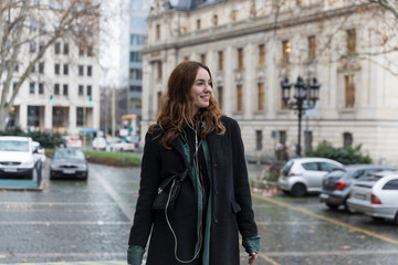 Fototapeta premium Young Urbanite Woman with Genuine Smile Looking Away in City