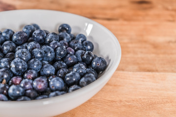 Blueberries in a white bowl on a Indian Wood Finish Table.