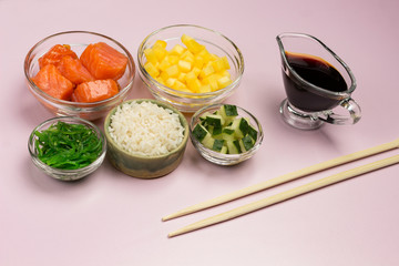 Set of raw vegetables, red fish, rice, soy sauce in glass bowls. Hawaiian dish. Bamboo chopsticks