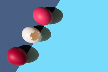 Three eggs are laid on the edge of the frame in a row. Two eggs are pink. One egg is white. the shell of a white egg has a hole in the middle. There is a place for the inscription.
