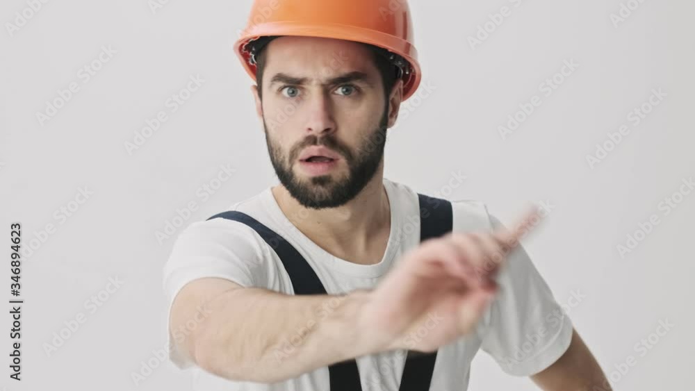 Sticker serious negative young bearded man builder isolated over white wall background in helmet make stop g