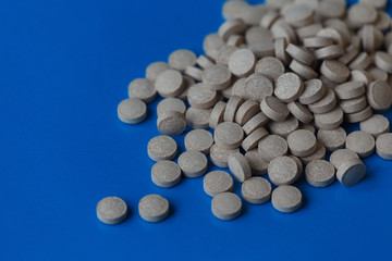 Brewer's yeast tablets on a blue background, selective focus, shallow depth of field. Medical concept, treatment, health