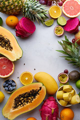 Flat lay tropical exotic fruits with copy space. Healthy summer food ingredients: papaya, pitaya, pineapple, orange, lime, grapes and mango.