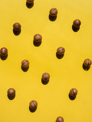 macadamia whole nuts pattern on yellow background, vertical
