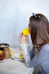 A girl in a crown sniffs a flower. The Queen is holding a yellow flower. Wedding gown. Scents of spring.