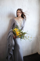A gorgeous brunette in a gray dress embroidered with lace and stones with a long train. Bride with...